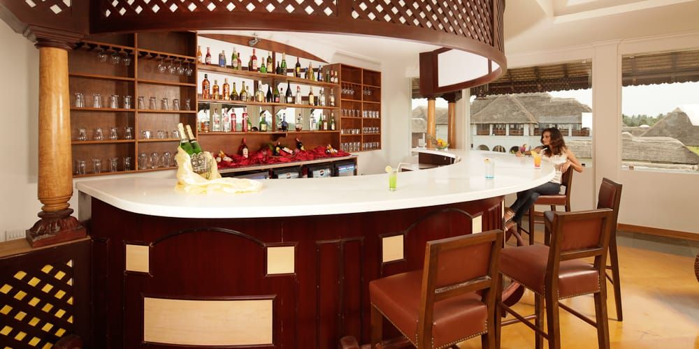Curved indoor bar counter with wooden panelling, bar stools and bottle shelves