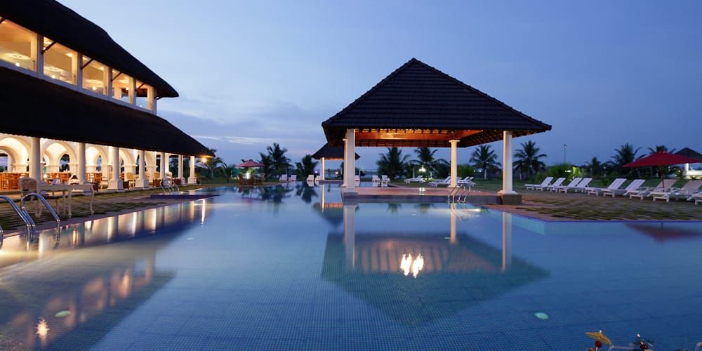 Swimming pool reflecting the illuminated Sunken Bar pavilion at twilight
