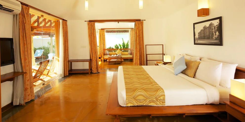 Presidential Pool Villa bedroom with a king size bed and adjoining living area at Le Pondy
