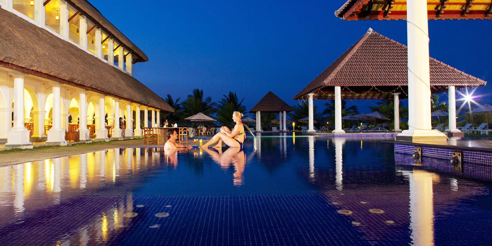 Le Pondy swimming pool and poolside resort buildings illuminated at night