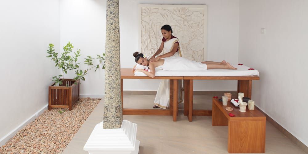 A therapist administering a massage in an open-sided room with a stone pillar